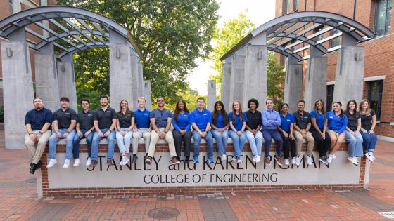 Group of Engineering Ambassadors sitting on Pigman College of Engineering sign in engineering courtyard